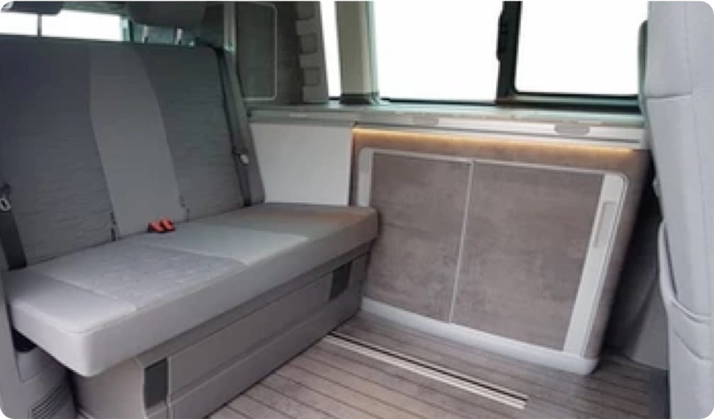 A photo of the rear seats and worktop inside of a VW campervan.